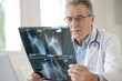 © goodluz - Portrait of senior doctor examining X-ray