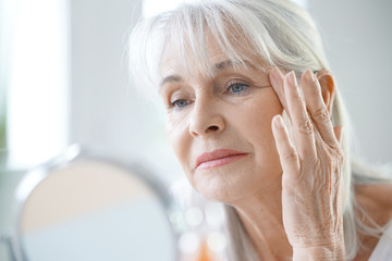 Wall Mural - Portrait of senior woman applying anti-aging cream