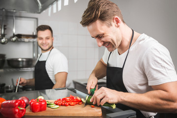 Wall Mural - Chef cutting vegetables and his coworker cooking