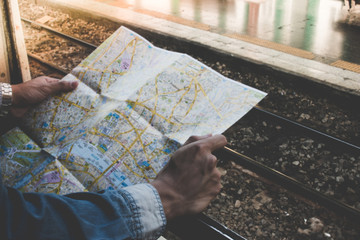 Young traveler holding travel map outside train window on a platform in the train station. Concept travel by train.