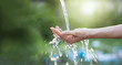 Water pouring in woman hand on nature background, environment concept