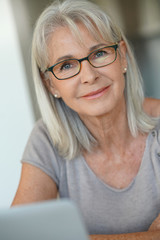 Wall Mural - Senior woman with eyeglasses using laptop