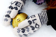 Hands in woolen mittens hold  Christmas ball on snow background