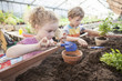 © Lumi Images - Two children in greenhouse planting plants