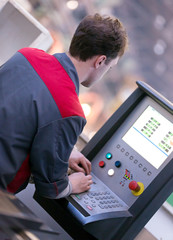 factory man worker adjusts cnc machine program during production process