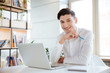 © Drobot Dean - Happy man dressed in white shirt using laptop computer.