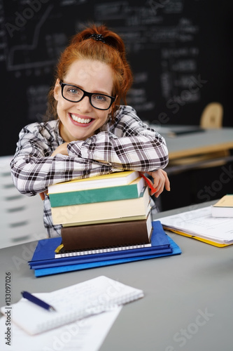 Fotografía motivierte studentin stützt sich auf einen stapel bücher