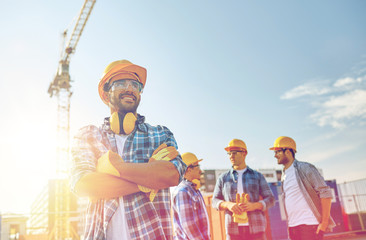 Poster - group of smiling builders in hardhats outdoors