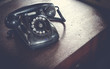 © wittayayut - Black antique vintage analog telephone dialing or scrolling phone on wooden table. Contact us concept.