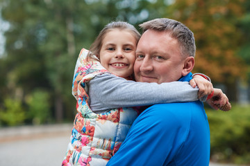 Smiling father and daughter hugging in a park