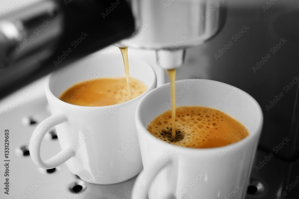 Fresh espresso pouring into cups from coffee machine