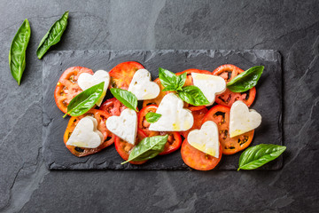 Caprese salad with tomatoes, cheese hearts, basil. Valentine day menu