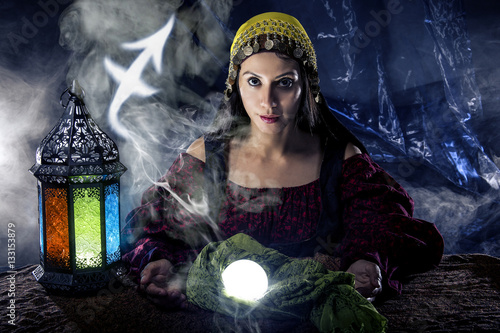 Fotografie, Obraz Psychic or fortune teller with crystal ball and horoscope zodiac sign of Sagitar