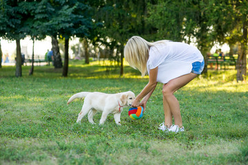 girl playing with her puppy in the park in spring