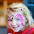 Cute little girl getting her face painted like a butterfly by face painting artist. Kids animation at the party.