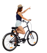 Back View Of Pointing Woman With A Bicycle. Cyclist Sits On The Bike. Rear View People Collection.  Backside View Of Person. Isolated Over White Background. Girl Cyclist Is Crossing His Frame.