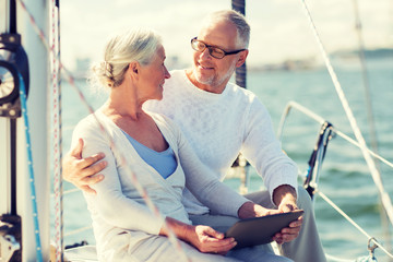 Poster - senior couple with tablet pc on sail boat or yacht