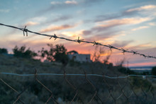 Barbed Wire In Front Of Villa And Sunset
