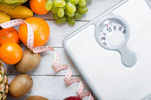 Fotomural Stack of fruits, white weight scale and tailor meter on wooden board