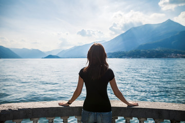 Wall Mural - Back view of young woman relaxing on terrace on lake Como, Italy