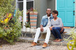 © Monkey Business - Young couple sit looking to camera outside their new house