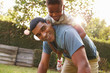 © Monkey Business - Young black boy playing on dad’s back in a garden, low angle