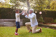 © Monkey Business - Black grandfather plays with grandson in garden, full length