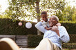 © Monkey Business - Young black boy embracing grandfather sitting in garden
