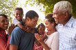 © Monkey Business - Multi generation black family look at each other in garden