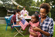 © Monkey Business - Black mother and baby holding flag at 4th July garden party