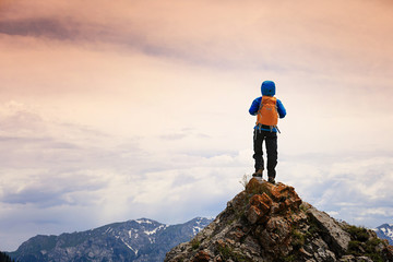 successful woman backpacker hiking on mountain peak cliff