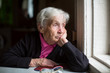 © De Visu - An elderly woman sadly looking out the window. Melancholy and depressed.