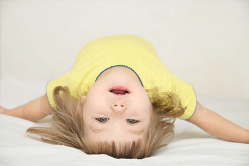 Wall Mural - happy funny little girl arched back lying on bed isolated, hap