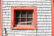 Window with peeling red paint in an old sea shanty