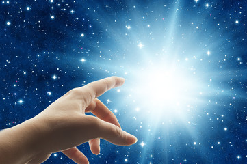 Wall Mural - woman hand touching a divine light in the universe like a spiritual mystical concept