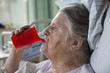 Seniorin im Krankenhaus trinkt aus einer Schnabeltasse