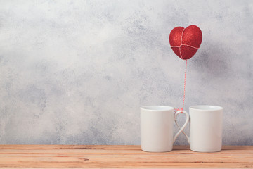 Wall Mural - Valentines day concept with coffee cups and heart shape balloon over rustic background