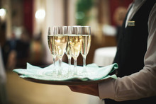 Waiter Serving Champagne On A Tray At The Hotel Restaurant