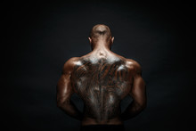 Unrecognizable Muscular Man With Tattoo On Back Against Of Black Background. Isolated.