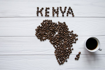 Wall Mural - Map of the Kenya made of roasted coffee beans laying on white wooden textured background with  cup of coffee and space for text