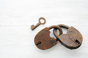 Old rusty padlock on wooden white background