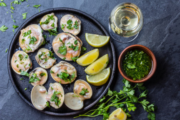 Raw clams with lemon, herbs and white wine, slate background