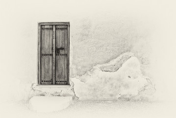 Sepia image of a traditional Arabian carved wooden door with a step in a crumbling plaster wall of a restored house in the Arabian Gulf.