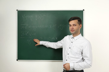 Canvas Print - Handsome young teacher explaining math formulas written on blackboard