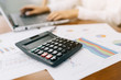 © interstid - Close up shot of calculator with businesswoman working in background