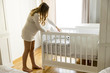 © BGStock72 - Pregnant woman setting up baby crib smiling