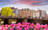 Fototapeta Tulipany - Traditional old buildings and and boats in Amsterdam, Netherlands