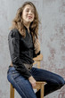 © rogkoff - Young girl with curly hair in a black shirt, jeans and high boots cowboy western style