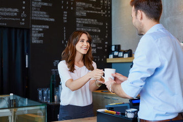 Canvas Print - Young barista serving coffee to male customer in cafe