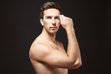 Poster - Young man touching his face on black background